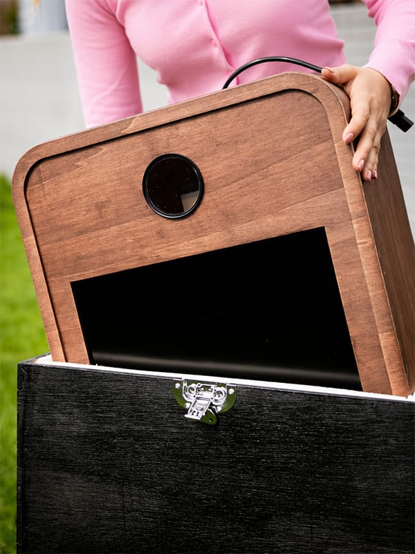 Houten fotobooth die in een transportkoffer wordt geplaatst tijdens de opbouw op een buitenlocatie.